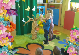 Dzieci ozdabiają wiosenne drzewo.